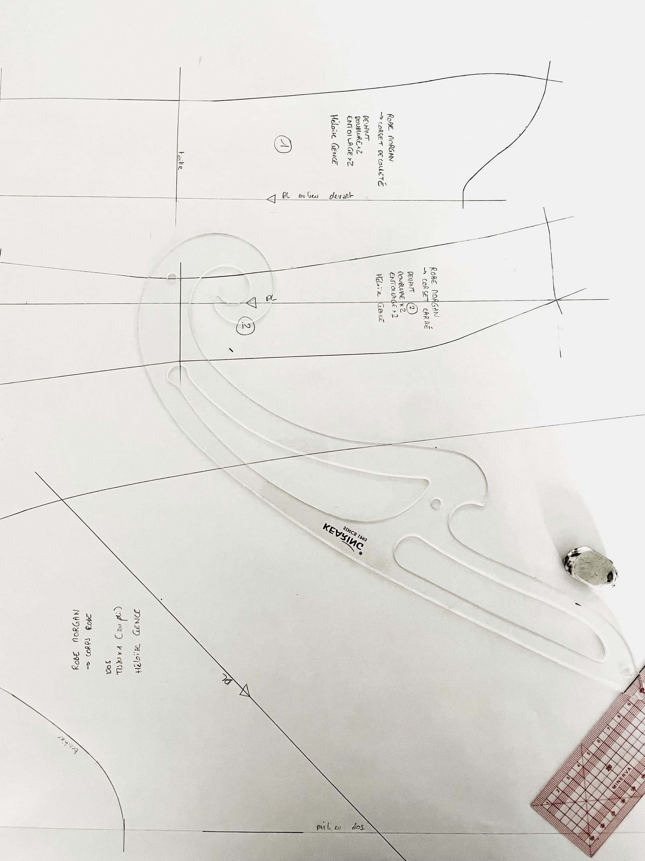 Un patron de robe tracé sur papier, règle perroquet et crayon posés dessus